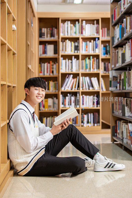 倚在书架上看书的学生