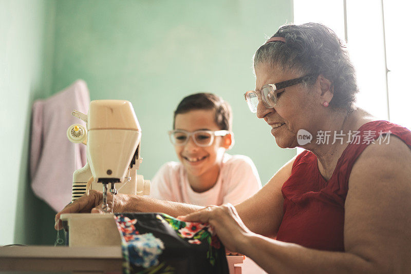 男孩看着他的祖母做针线活