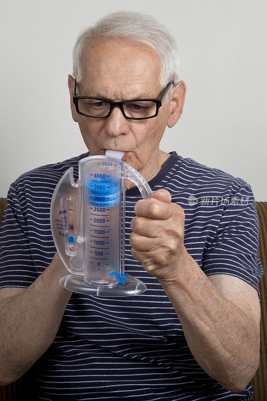 老人在家里用肺活量计专心观察