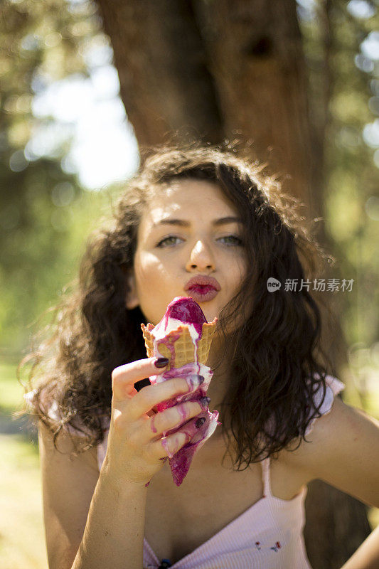 年轻女子在阳光明媚的户外吃冰淇淋