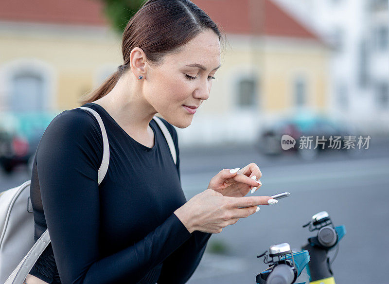 一名女子用手机应用程序解锁一辆电动滑板车