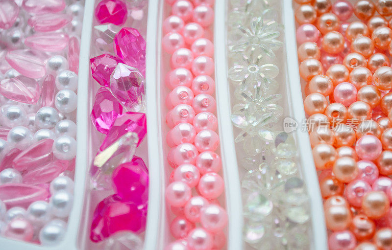 特写各种珍珠和珠粉，橙色，白色，紫罗兰色和透明的工艺品。作为一个微妙的背景。有选择性的重点