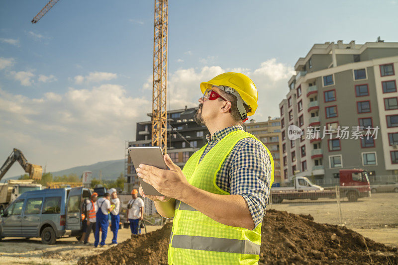 工程师、建筑督察或建筑师在施工现场前手持数码板