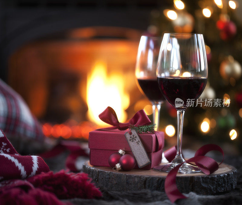 圣诞红酒和礼物在壁炉和圣诞树前