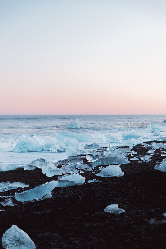 冰岛冬季日落时美丽的黑色沙滩和冰山碎片