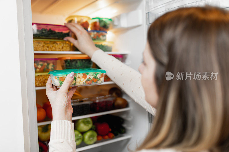 从冰箱里拿生食物的女人