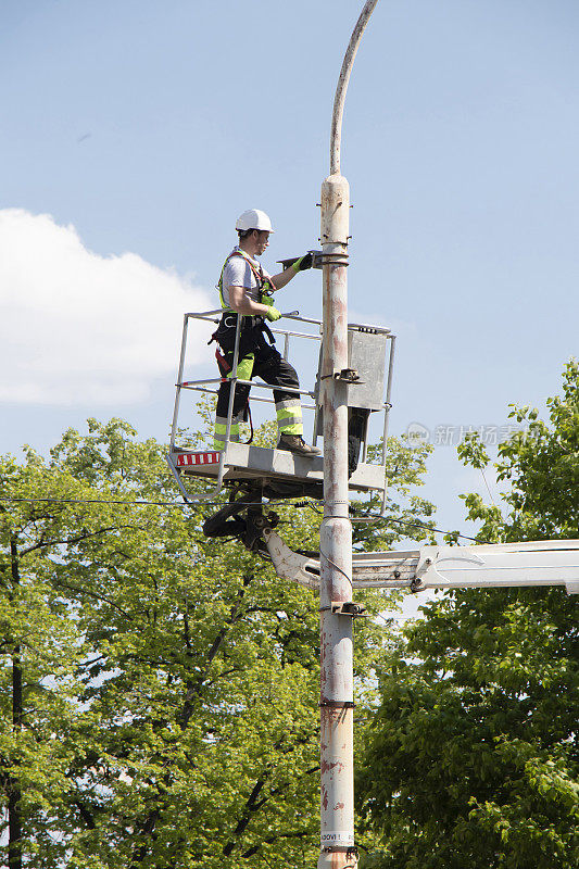 工人在吊篮上安装路灯灯杆上的金属支架