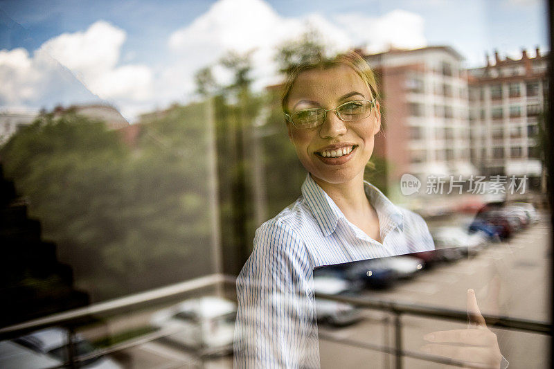 一位女商人站在窗边，一边思考一边谈生意