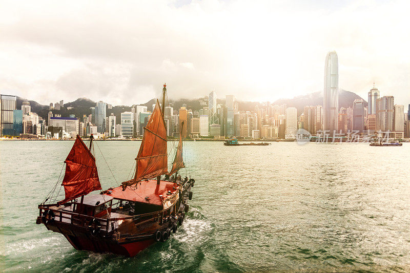 日落时分，传统的中国舢板船在维多利亚港驶向香港岛