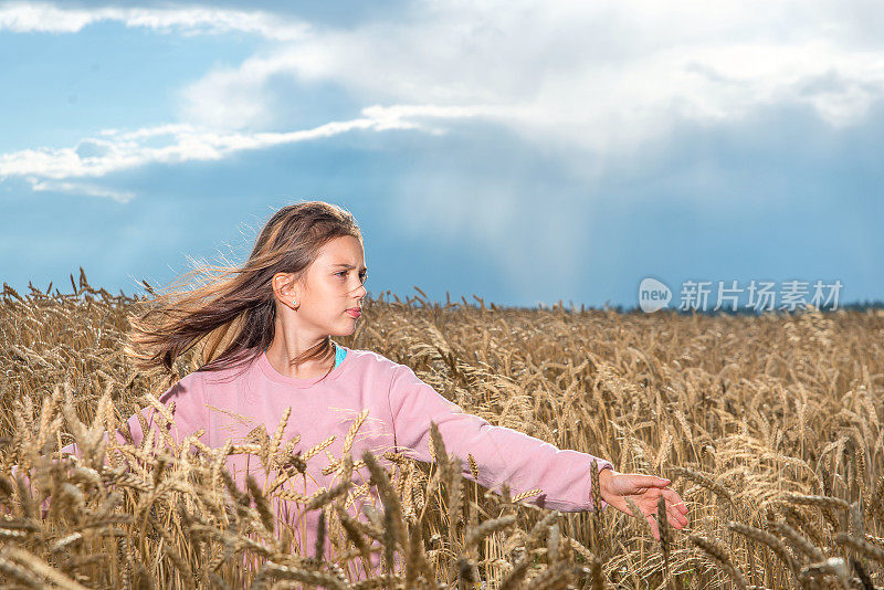 一个女孩在夏天的麦田里举起双手。