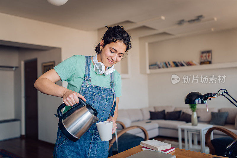 一个快乐的年轻女人在早上煮咖啡