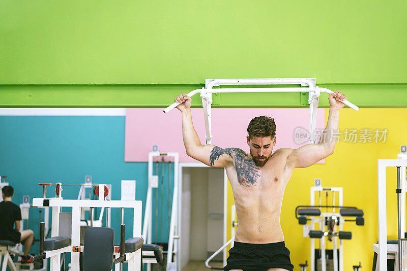 肌肉男在健身房做引体向上，在健身俱乐部锻炼。