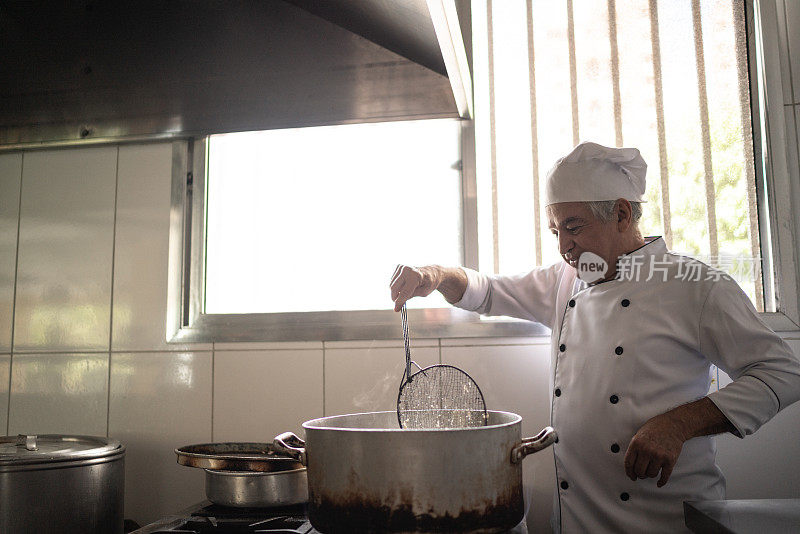 高级厨师在一个工业厨房里准备油炸食品