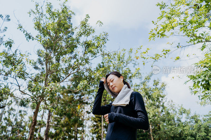 年轻的亚洲妇女运动后，在公园用毛巾擦脸