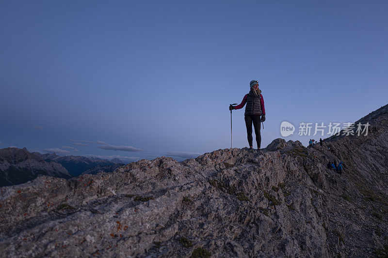 女人在日出时沿着山脊徒步