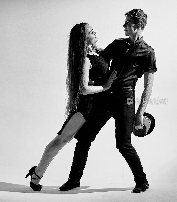 两个年轻的舞者在跳拉丁美洲舞时热情洋溢地看着对方。黑白图片