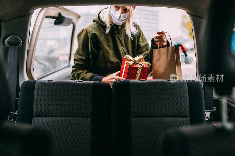 2019冠状病毒病期间，一名年轻女子在圣诞购物后在车上打包圣诞礼物