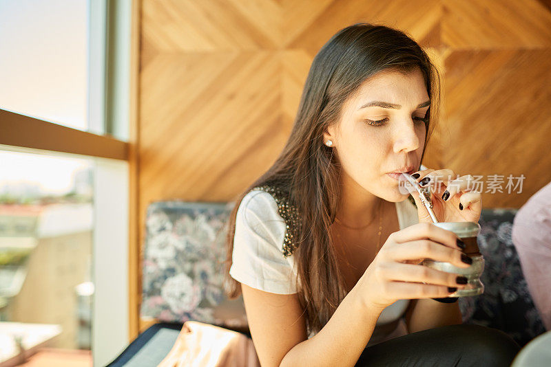 年轻女子用可重复使用的杯子和吸管喝马黛茶