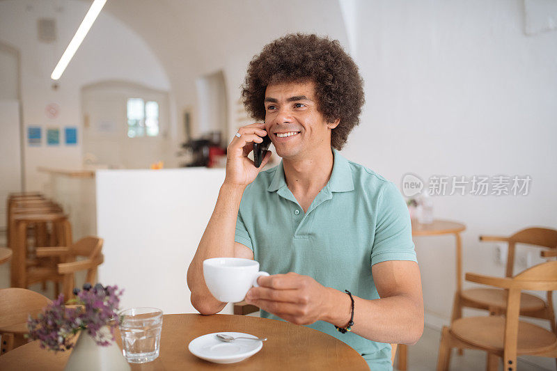 一个微笑的非洲裔美国人在咖啡馆里用智能手机