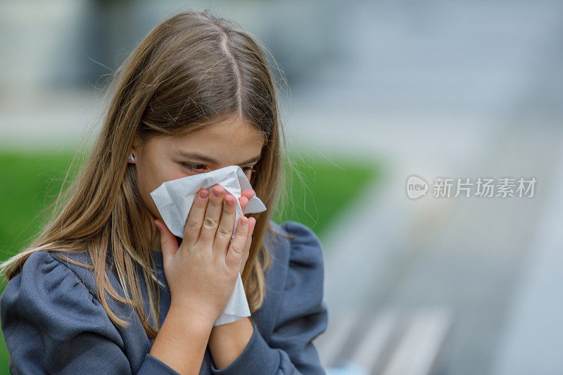感冒和高烧的生病女孩在户外打喷嚏和咳嗽。