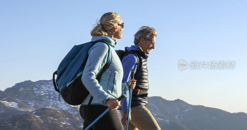 成年夫妇沿着长满青草的山脊徒步旅行