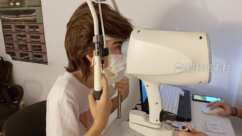 医生在诊所用现代化的设备检查一个男孩的视力。