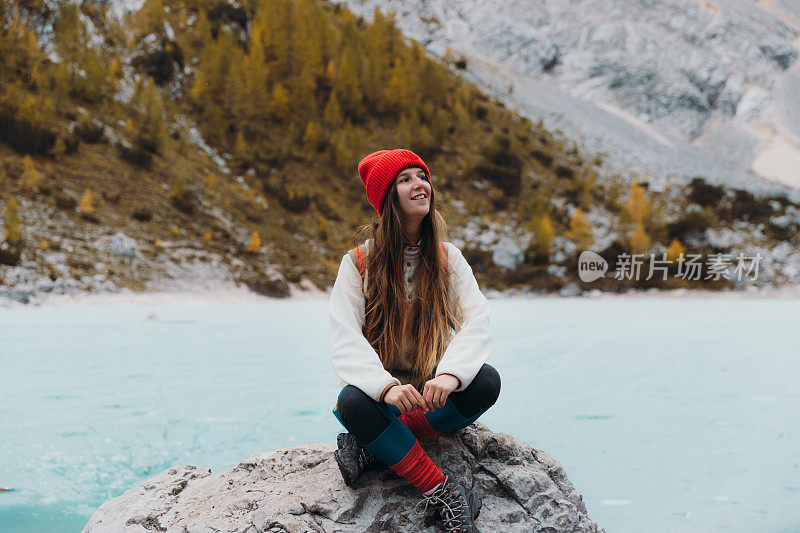 快乐的女旅行者坐在岩石上享受风景的tuquouise冻结高山湖在阿尔卑斯山