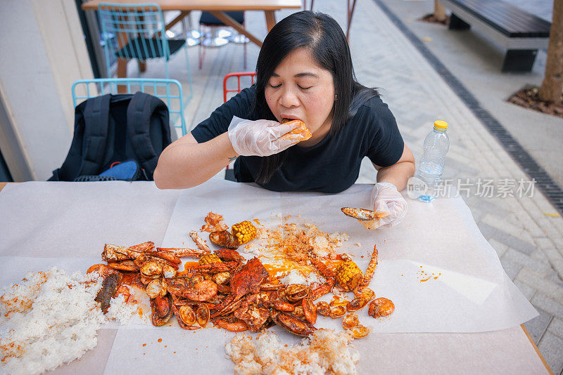 高视角的女人坐在餐桌旁，吃海鲜和米饭堆