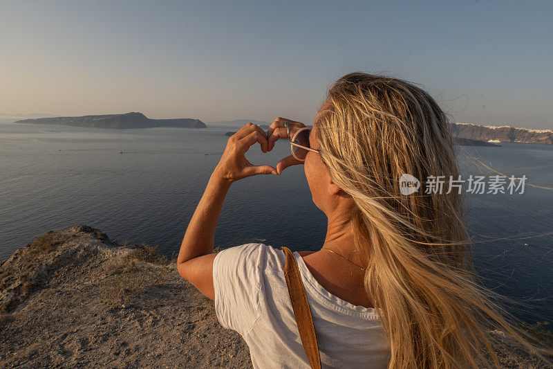 一名女子在希腊风景画上做了一个心形手指架