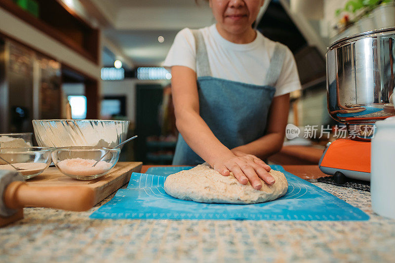 亚洲华人微笑的面包师妇女在厨房准备面团