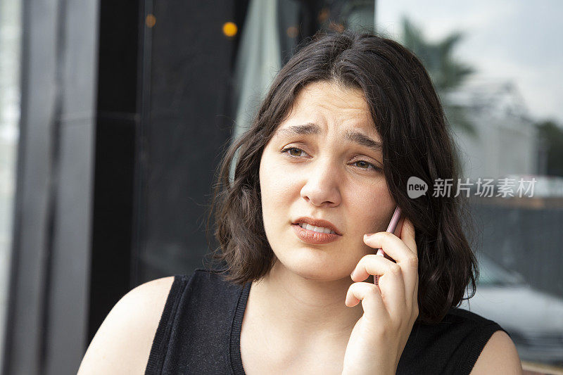 一个沮丧和心烦意乱的女人坐在咖啡馆里打电话的肖像