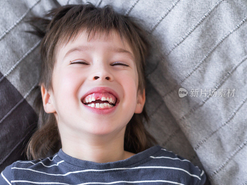 笑着的孩子露出一排牙齿上的洞。刚才掉了一颗门牙。牙科医生的牙床近照。