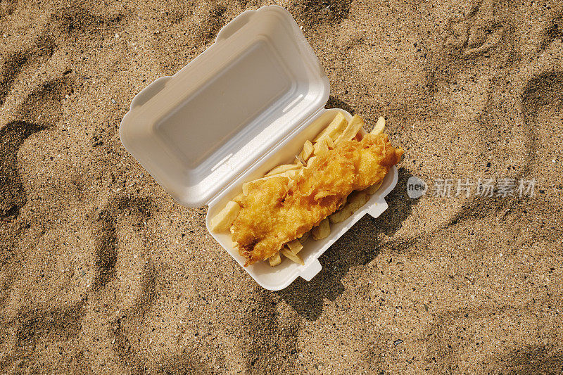6月的一个阳光明媚的日子，康沃尔郡纽基海滩上的一盒鱼和薯条。