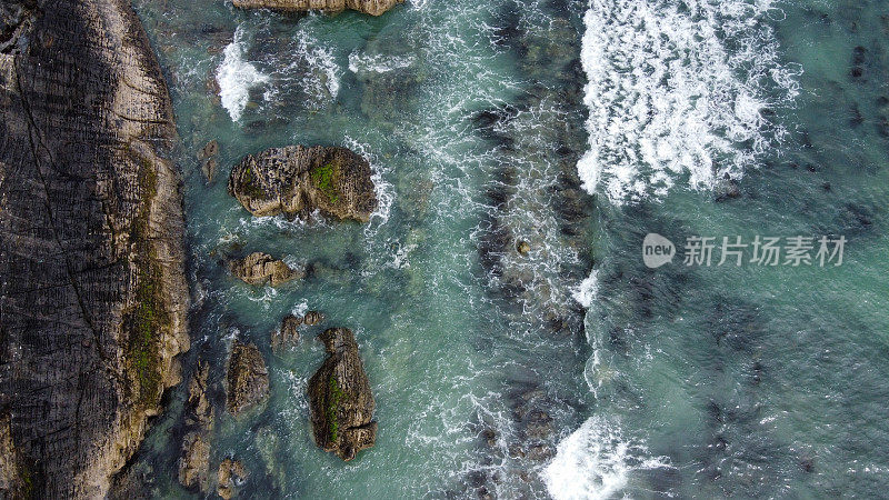 俯视，海浪拍打着凯尔特海的岩石海岸。浪花上的白色泡沫。大西洋的海岸线蓝绿色的海水。令人惊叹的海滨风景。
