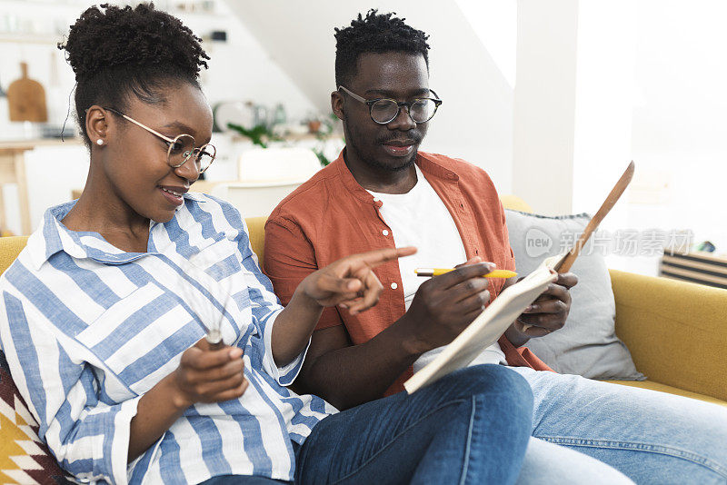 快乐的非洲裔夫妇阅读食谱，选择烘焙什么