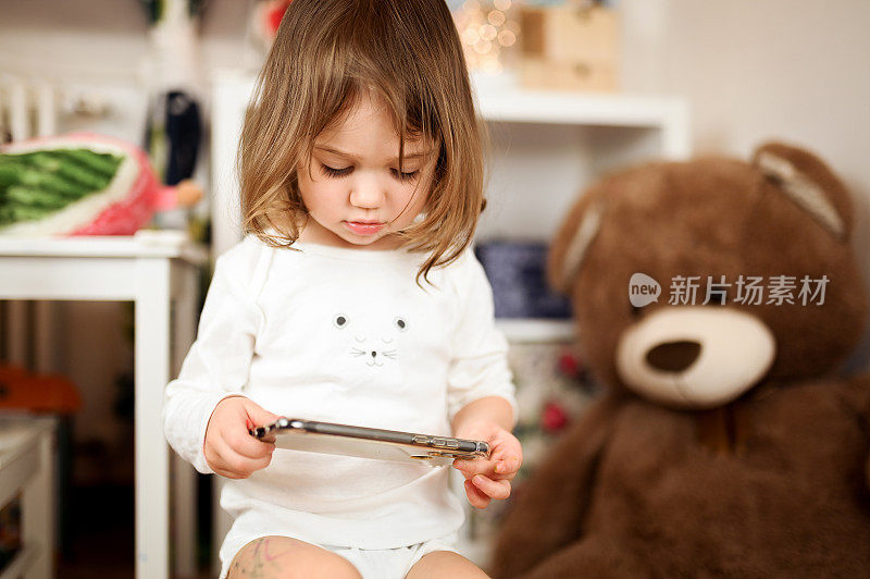 可爱的小女孩拿着智能手机，小女孩用手机。玩智能手机。