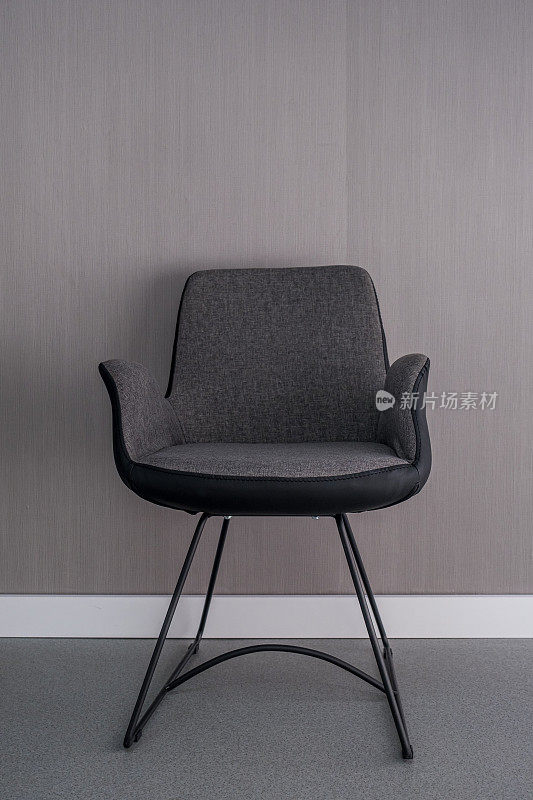 空的深灰色和黑色的椅子在灰色的墙壁