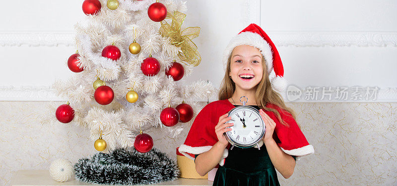 新年倒计时。女孩小孩圣诞老人帽子服装时钟兴奋快乐的脸数时间到新年。午夜前的最后一分钟。最后一分钟的新年除夕计划其实很有趣