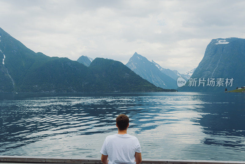 挪威一名男子凝视峡湾景色的后视图