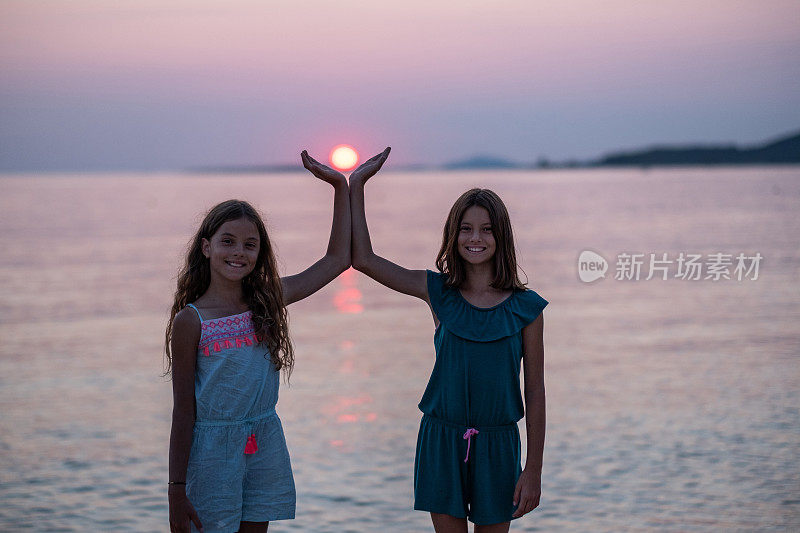 日落时分，两个十几岁的女孩在海滩上拍照。