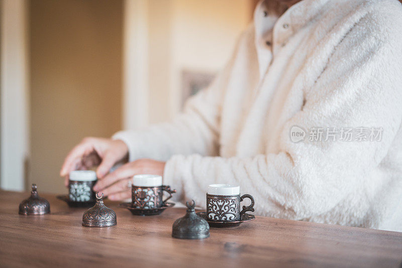 妇女们在厨房的木桌上准备土耳其咖啡的玻璃杯