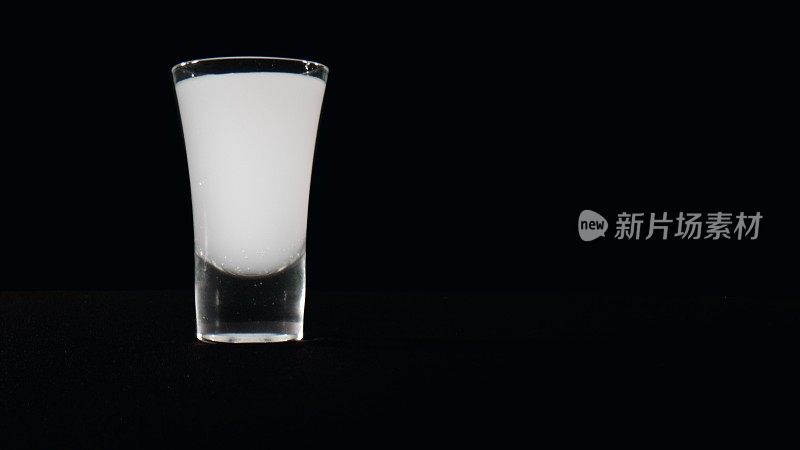 苏打水和伏特加在一个黑色的玻璃杯里一起反应