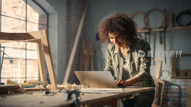 一个多民族艺术家使用笔记本电脑的特写肖像。黑人创意女性打字电子邮件，浏览互联网，在阁楼工作室用墙上的工具做一个在线项目。