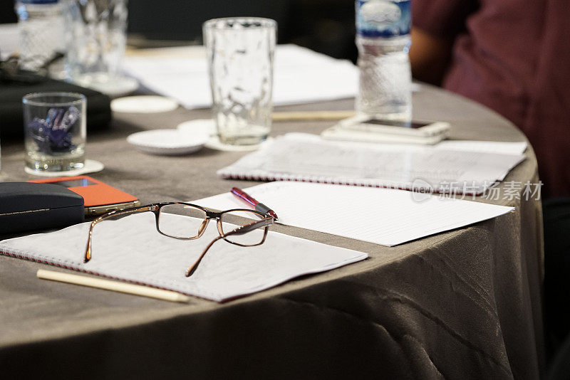会议室桌子上的空白笔记本、眼镜和笔