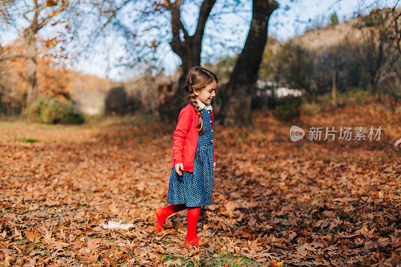 小女孩赤脚走在满是干枫叶的森林里