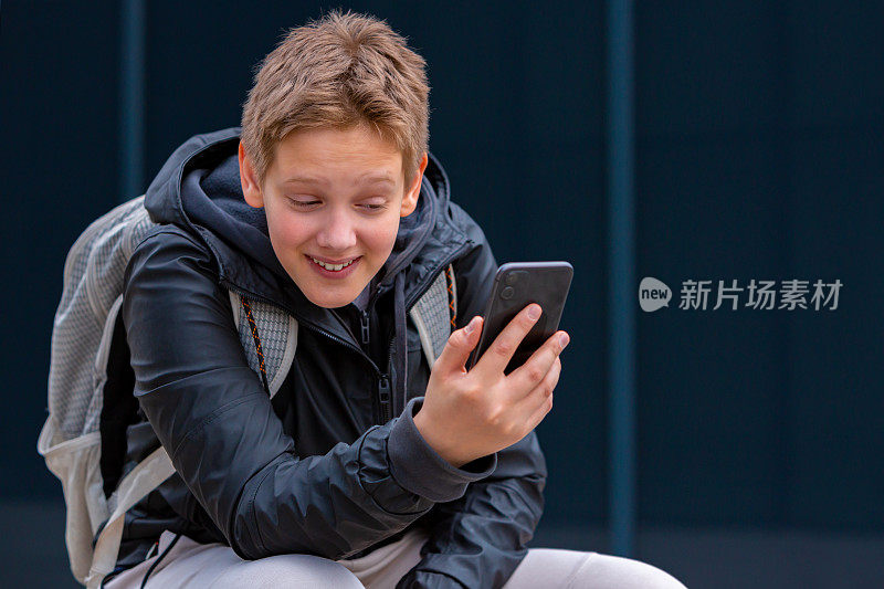 十几岁的男孩微笑着用手机和朋友视频聊天