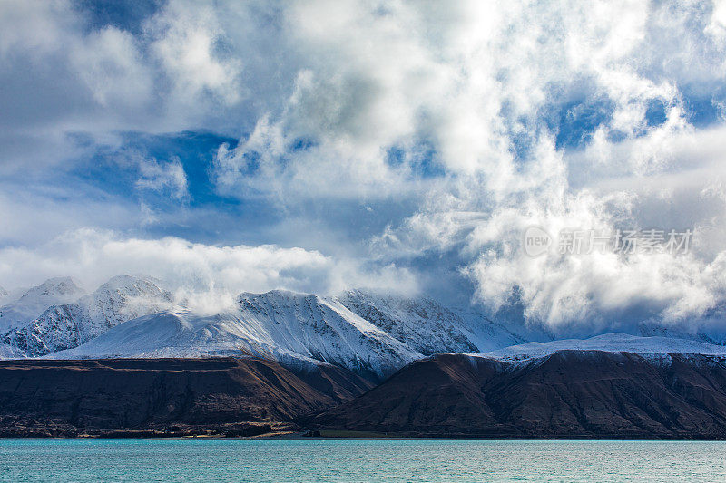 绿松石湖与戏剧性的景观雪山的背景