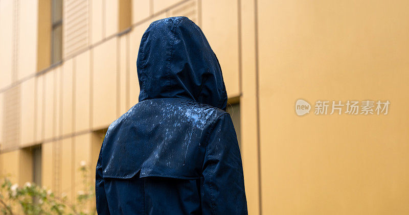 一个穿着蓝色雨衣的女人站在雨中。