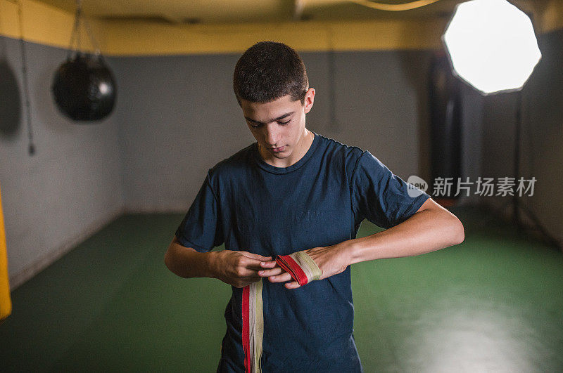 一名年轻的男运动员在训练开始前将保护绷带缠在手上