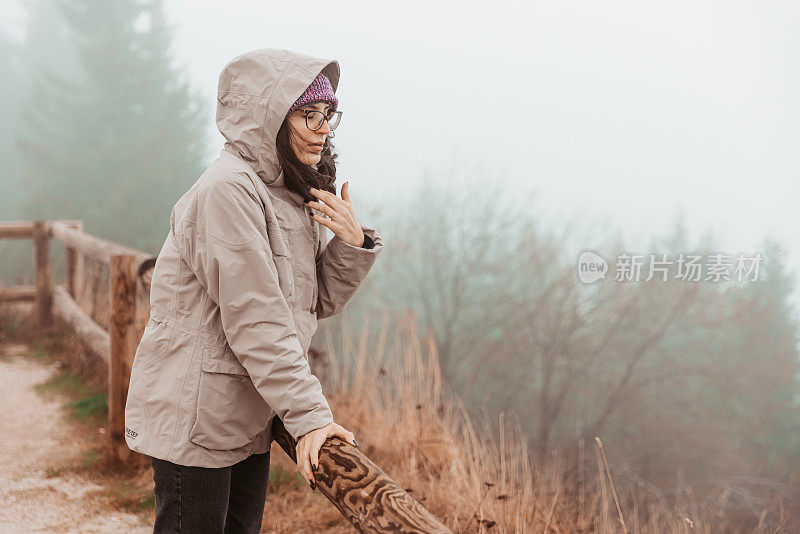 一个年轻的女性徒步旅行者在风和雾的肖像-股票照片